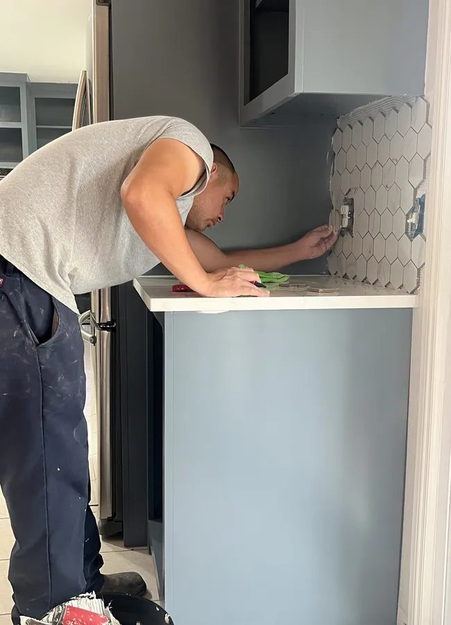 Jacob Vasquez setting a hexagon tile backsplash in a kitchen
