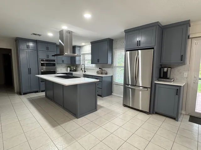 The same kitchen after: slate-blue custom cabinets, quartz and a new island
