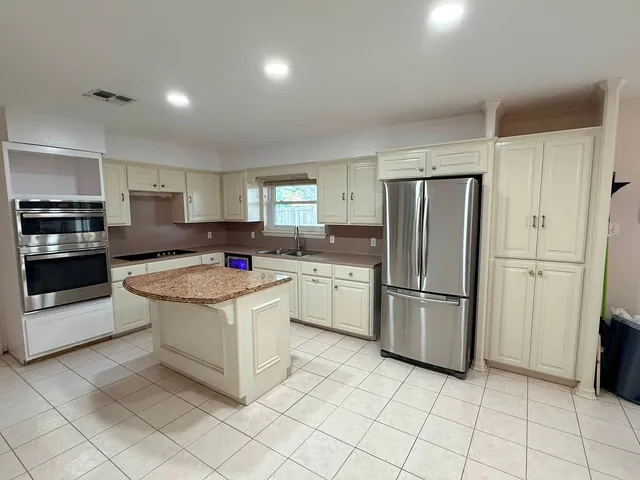The kitchen before: cream cabinets, laminate counters and a granite island