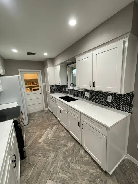 After: White cabinets, new countertops and black herringbone tile.