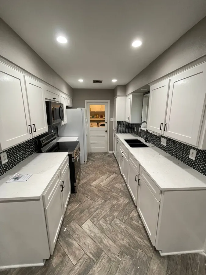 White galley kitchen with a black tile backsplash