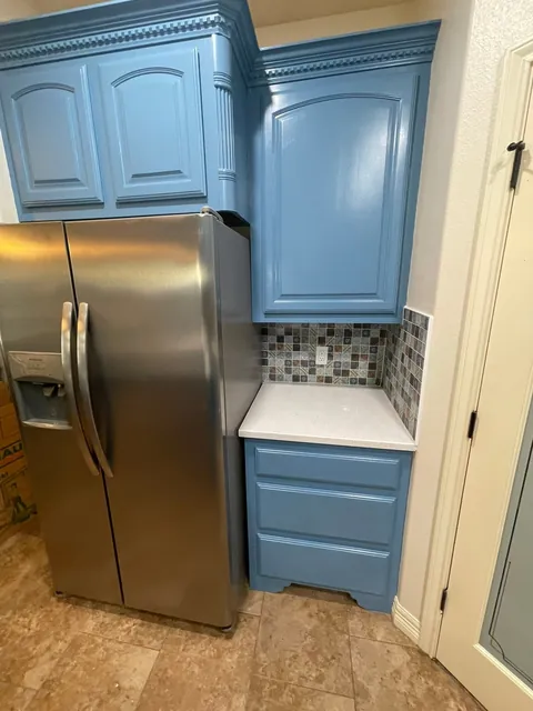 Painted blue cabinets beside the refrigerator