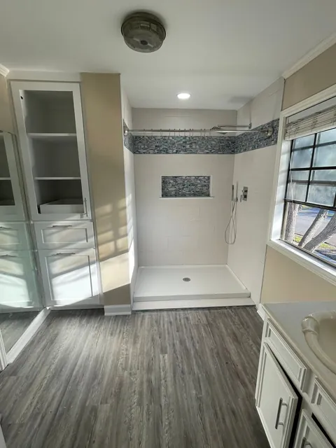 Walk-in tile shower with a frameless glass panel, wall niche and rain head