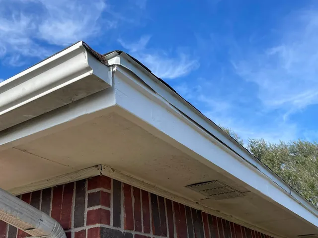 New white fascia and soffit at the roof corner of a brick house
